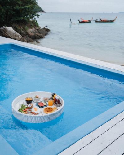 un plateau en plastique contenant de la nourriture dans une piscine dans l'établissement Casa De Lipe, à Koh Lipe