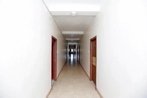 un pasillo vacío en un edificio con paredes blancas y un pasillo en NEW JANKI GUEST HOUSE, en Jamnagar