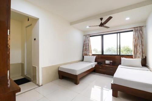 1 dormitorio con 2 camas y ventilador de techo en NEW JANKI GUEST HOUSE, en Jamnagar