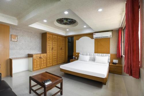 1 dormitorio con 1 cama grande y 1 mesa en NEW JANKI GUEST HOUSE, en Jamnagar
