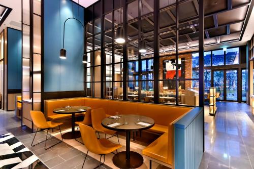 a restaurant with two tables and yellow chairs at Four Points by Sheraton Taipei Bali in Bali