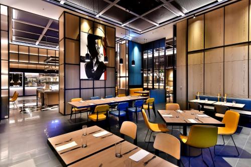 a restaurant with wooden tables and yellow chairs at Four Points by Sheraton Taipei Bali in Bali