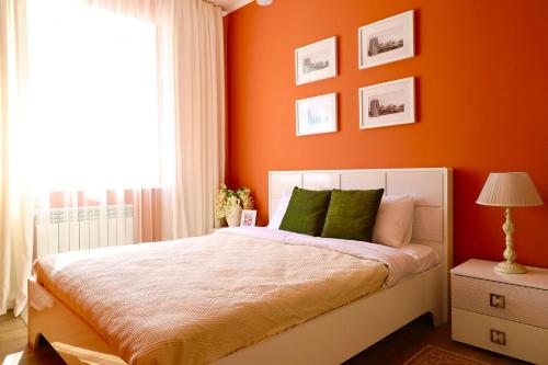 a bedroom with orange walls and a bed with green pillows at Berry House close to Talgar Almaty in Kaynazarka