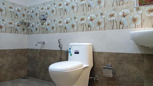 a bathroom with a toilet and flowers on the wall at AbbA Marari Beach Villas & Homestay Mararikulam in Alleppey