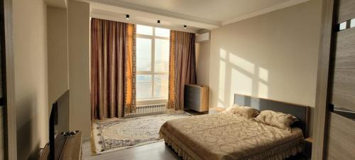 a bedroom with a bed and a large window at ABYROY-RESIDENCE in Atyrau