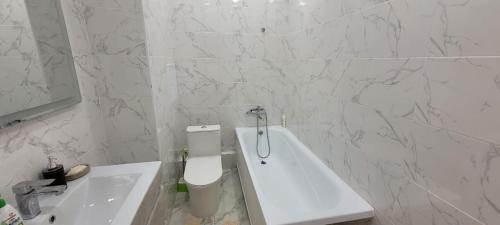 a white bathroom with a toilet and a sink at ABYROY-RESIDENCE in Atyrau