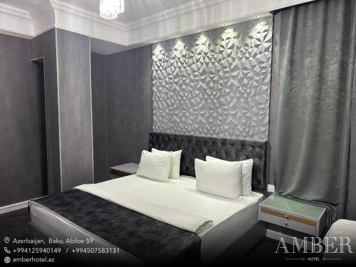 a bedroom with a bed with white sheets and pillows at Amber Hotel in Baku