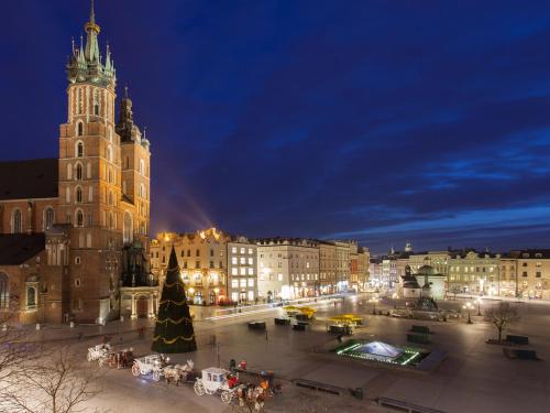 a city with a christmas tree and a clock tower at Hotel Betmanowska Main Square Residence Adults Only in Kraków