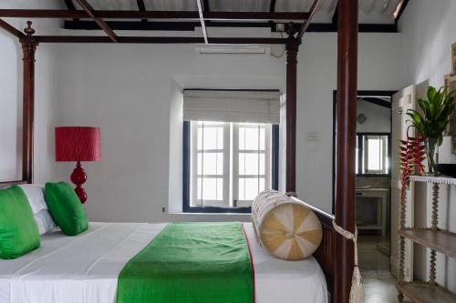 um quarto com uma cama com almofadas verdes e uma janela em Coco Tangalla em Tangalle