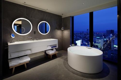 a bathroom with a large tub and a large window at W Osaka in Osaka