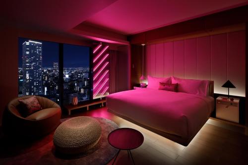 a pink bedroom with a bed and a chair at W Osaka in Osaka