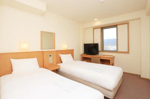 a hotel room with two beds and a television at Smile Hotel Nara in Nara