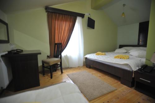 a bedroom with a bed and a desk and a window at Garni Hotel City in Kruševac
