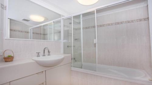 La salle de bains blanche est pourvue d'une douche et d'un lavabo. dans l'établissement Unit 1 The Rocks, à Coolum Beach