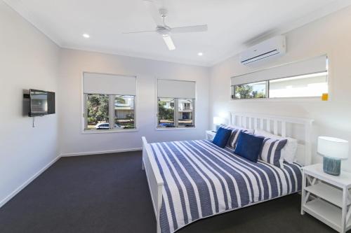 a bedroom with a bed and two windows at 11 Ann Street in Coolum Beach