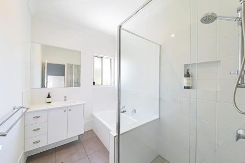 Un baño blanco con ducha y lavabo. en 11 Ann Street, en Coolum Beach