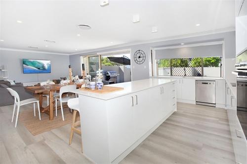a kitchen and dining room with white cabinets and a table at Beautiful Beach House in the Heart of Town in Coolum Beach