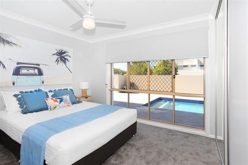 a bedroom with a bed and a swimming pool at Beautiful Beach House in the Heart of Town in Coolum Beach