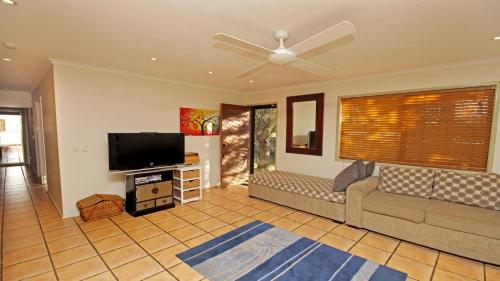 a living room with a couch and a flat screen tv at 15 Clematis Court in Marcoola