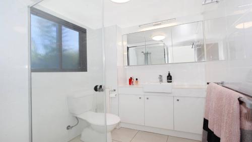 a white bathroom with a toilet and a sink at Unit 1 Phoenix in Coolum Beach