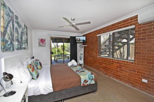 a bedroom with a bed and a brick wall at Red Door Beach House in Marcoola