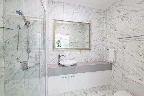 een witte badkamer met een wastafel en een douche bij Unit 8 Bronte of Coolum in Coolum Beach
