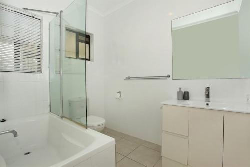 a white bathroom with a sink and a shower at 6 Petrie Avenue in Marcoola