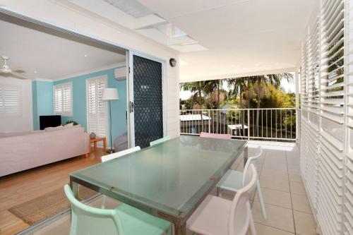 a dining room with a glass table and white chairs at Unit 4 Marcoola Sands in Marcoola
