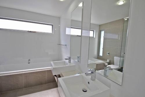 a bathroom with a sink and a tub and a mirror at 48 Boardrider Crescent in Marcoola