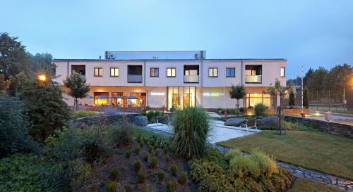 a large building with a garden in front of it at Wellness Hotel ABÁCIE in Nový Jičín