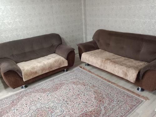 twee bruine banken in een woonkamer met een tapijt bij 2-х комнатная Казахстан 97 in Öskemen