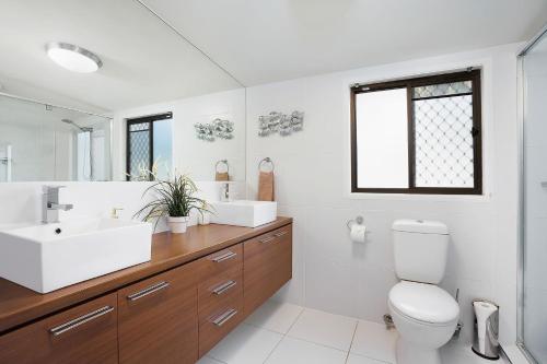 a bathroom with a toilet and a sink and a mirror at 22 Sorrento Avenue in Coolum Beach