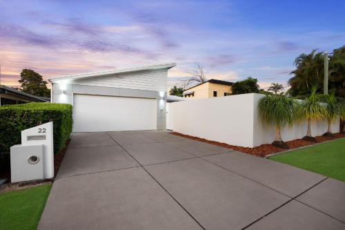 a white garage with a fence and a driveway at 22 Sorrento Avenue in Coolum Beach