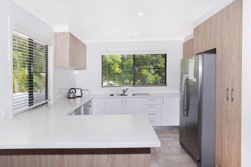 a white kitchen with a sink and a refrigerator at 8 Springfield Avenue in Coolum Beach