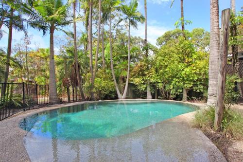 a swimming pool in a yard with palm trees at 8 Springfield Avenue in Coolum Beach