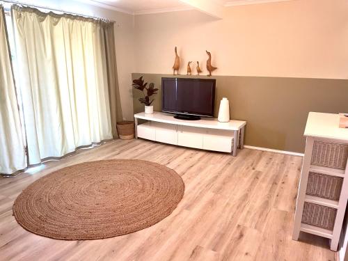 a living room with a flat screen tv and a rug at Yorks View in Kingscote