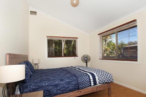a bedroom with a bed and two windows at 24 Sundew Street in Mudjimba