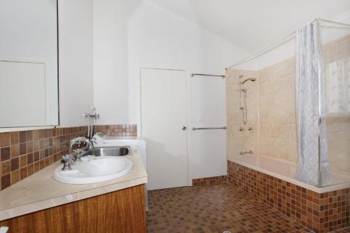 a bathroom with a sink and a shower and a tub at 24 Sundew Street in Mudjimba
