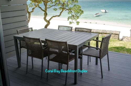 uma mesa e cadeiras num deque com praia em Coral Bay by Dream Escapes em Blue Bay