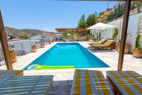 uma piscina com espreguiçadeiras e guarda-sóis em Cyprus Villages Kalavasos em Kalavasos