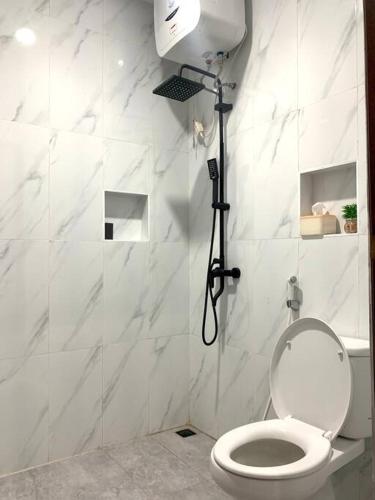 a white bathroom with a toilet and a shower at Davyn's House - Cozy and Private House in Lombok in Prampuan