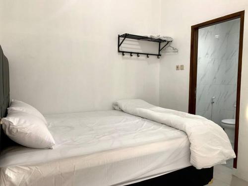 uma cama branca num quarto branco com uma casa de banho em Davyn's House - Cozy and Private House in Lombok em Prampuan