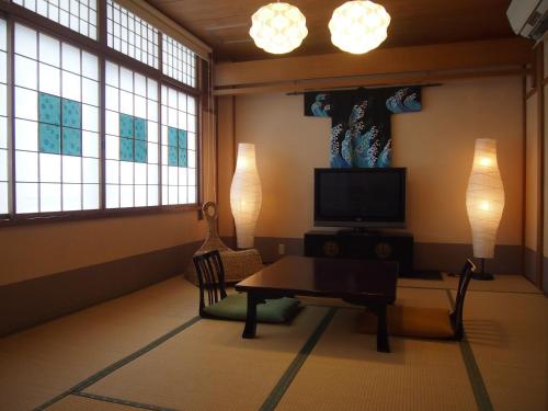a living room with a table and a tv and windows at Oyado Koto No Yume in Takayama