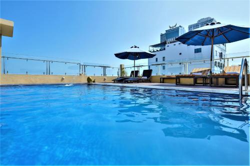 a swimming pool with blue water and umbrellas on a ship at Richico Apartments And Hotel in Da Nang
