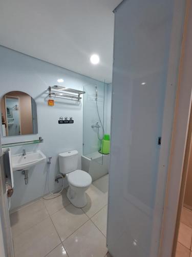 a white bathroom with a toilet and a sink at Christine Hotel Jogja in Yogyakarta