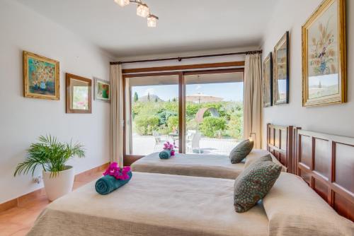 a bedroom with three beds and a large window at Ideal Property Mallorca - Ca na Siona 6 PAX in Alcudia