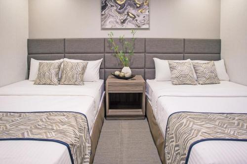 una habitación con 2 camas y un jarrón sobre una mesa en Anika Suites, en Cebú