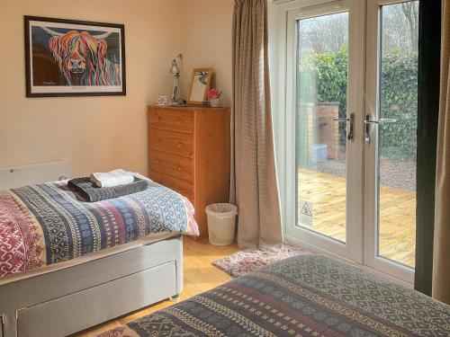 a bedroom with a bed and a dresser and a sliding glass door at Thistle Dubh in Drumnadrochit