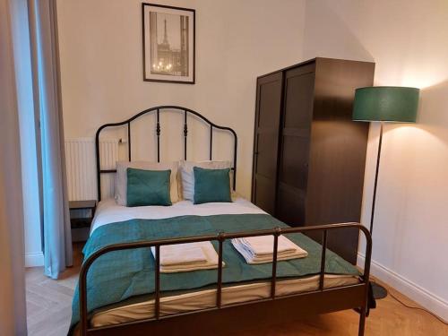 una cama con almohadas verdes y una lámpara en una habitación en Apartament Poziomkowa, en Przasnysz