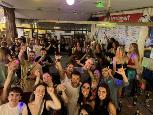 Un groupe de personnes debout dans une pièce avec les mains levées dans l'établissement Nana Backpackers Hostel, à Vang Vieng